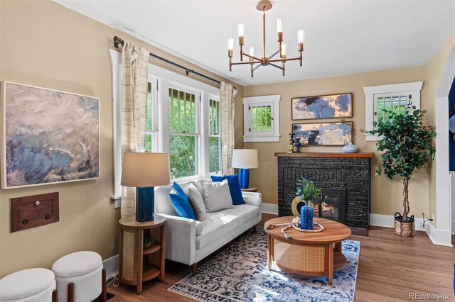 2271 Holly St, Denver, CO 80207 - living room featuring wood finished floors, a chandelier, baseboards, and a fireplace