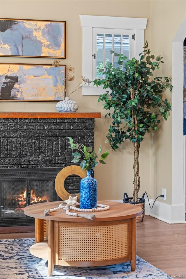 2271 Holly St, Denver, CO 80207 - living area featuring a warm lit fireplace, wood finished floors, and baseboards