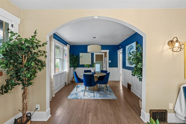 2271 Holly St, Denver, CO 80207 - dining space with a wainscoted wall, wood finished floors, a decorative wall, and arched walkways