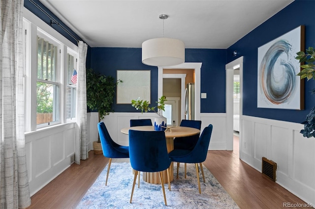 2271 Holly St, Denver, CO 80207 - dining area featuring wood finished floors, a wainscoted wall, and a decorative wall