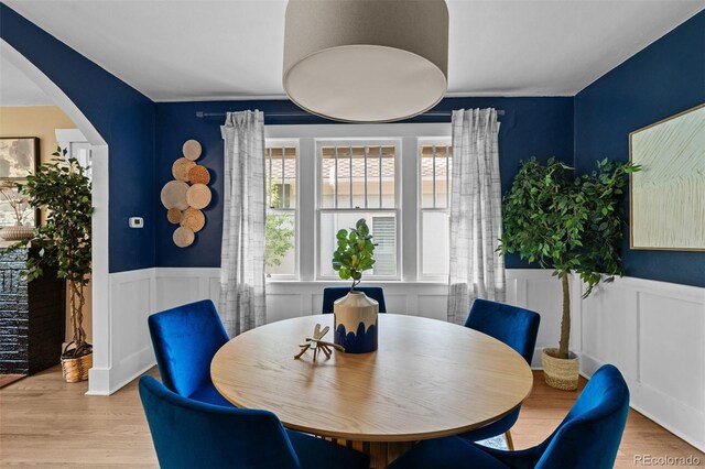 2271 Holly St, Denver, CO 80207 - dining area featuring a wainscoted wall, arched walkways, wood finished floors, and a decorative wall