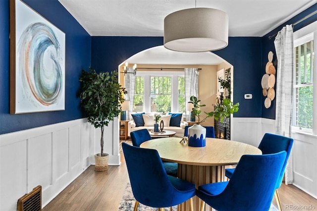 2271 Holly St, Denver, CO 80207 - dining room featuring a wainscoted wall, healthy amount of natural light, arched walkways, wood finished floors, and a decorative wall