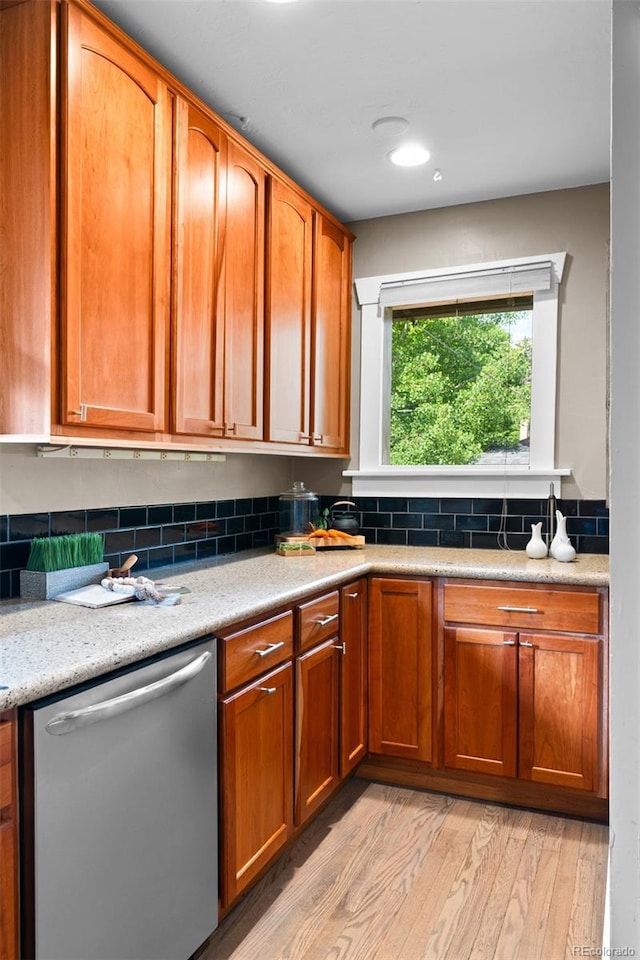 2271 Holly St, Denver, CO 80207 - kitchen featuring stainless steel dishwasher, light wood-style flooring, light countertops, and brown cabinetry