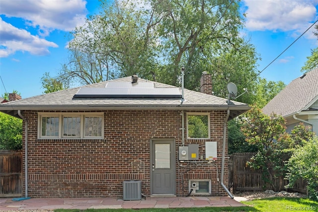 2271 Holly St, Denver, CO 80207 - back of house featuring brick siding, a chimney, solar panels, and a shingled roof