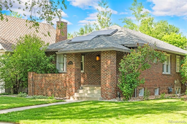 2271 Holly St, Denver, CO 80207 - view of front of property with solar panels, a chimney, brick siding, and a front lawn