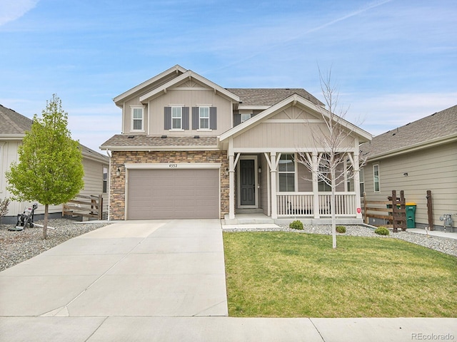 craftsman-style home featuring stone siding, a garage, a front yard, concrete driveway, and covered porch
