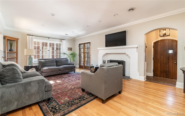 living room featuring crown molding, a fireplace, and light hardwood / wood-style flooring