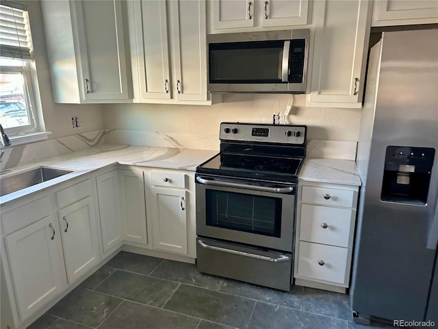 kitchen with sink, light stone countertops, white cabinets, and appliances with stainless steel finishes