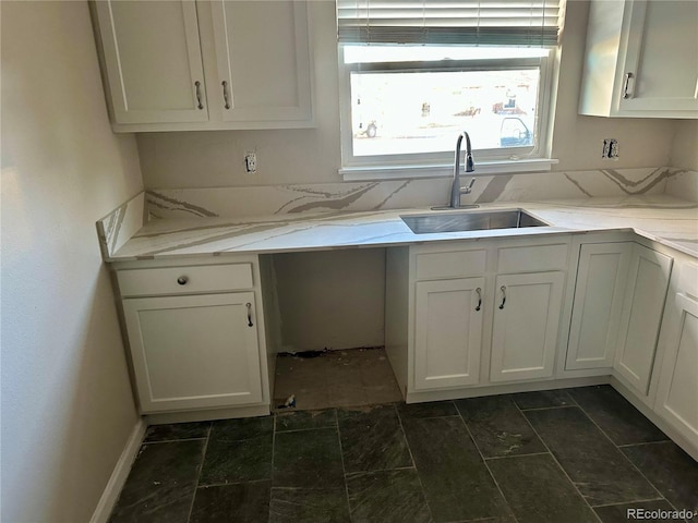 kitchen featuring white cabinetry, sink, and light stone counters