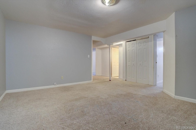 unfurnished bedroom featuring light colored carpet, a closet, and a textured ceiling