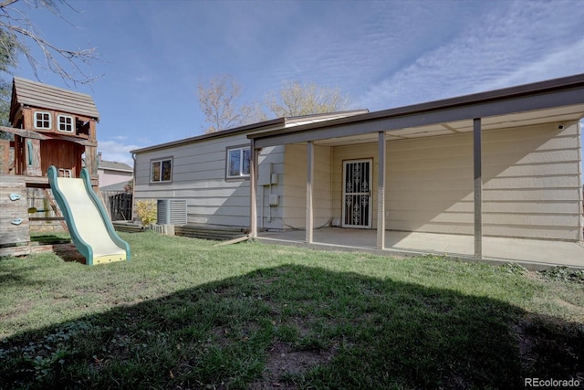 rear view of house featuring a yard and a playground