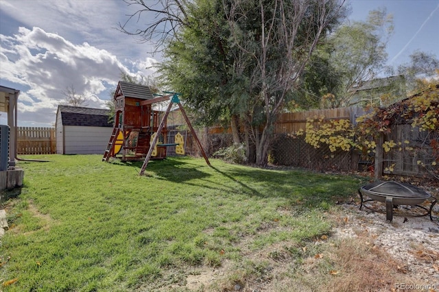 view of yard featuring a playground, a shed, and a fire pit