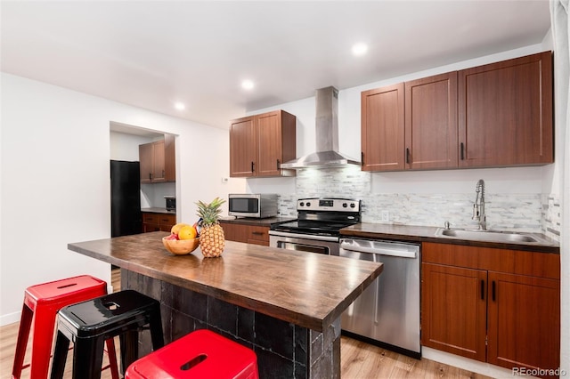 192 Little Creek Rd, Idaho Springs, CO 80452 - kitchen with stainless steel appliances, wall chimney range hood, a sink, light wood finished floors, and tasteful backsplash