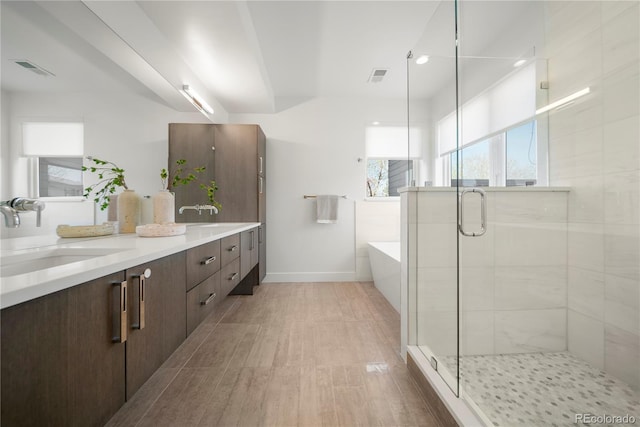 full bath featuring visible vents, baseboards, a sink, a shower stall, and a washtub