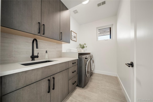laundry area featuring a sink, visible vents, cabinet space, and washing machine and dryer