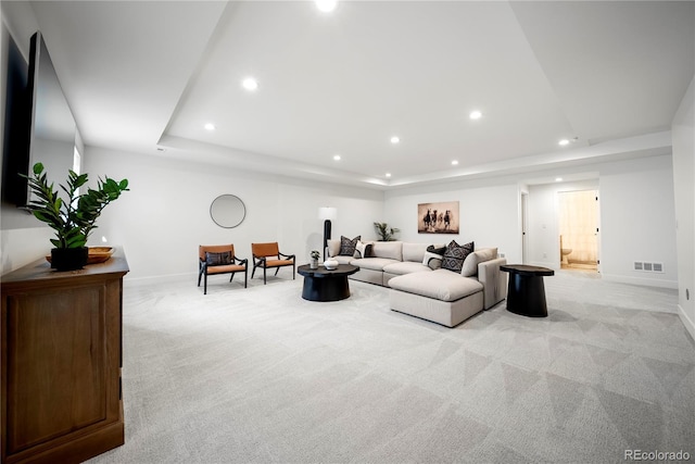 living area with light carpet, recessed lighting, visible vents, and a tray ceiling