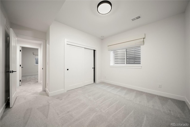 unfurnished bedroom with light carpet, a closet, baseboards, and visible vents