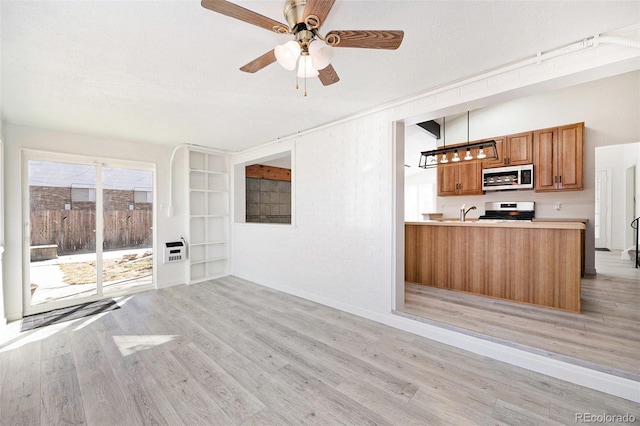 unfurnished living room with ceiling fan, brick wall, a textured ceiling, and light hardwood / wood-style floors