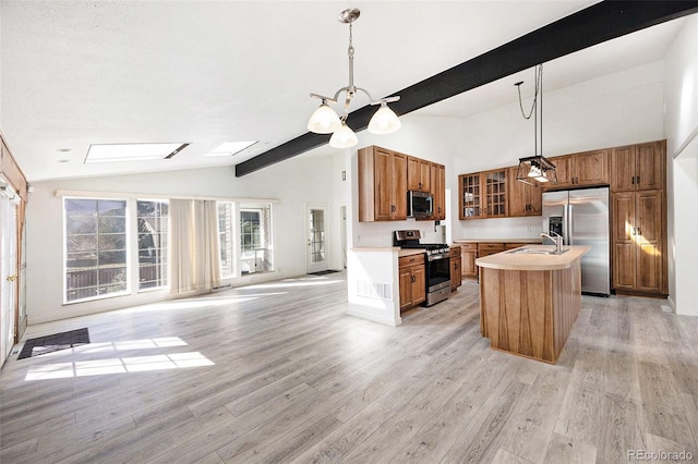 kitchen featuring pendant lighting, light hardwood / wood-style flooring, a kitchen island with sink, stainless steel appliances, and lofted ceiling with beams