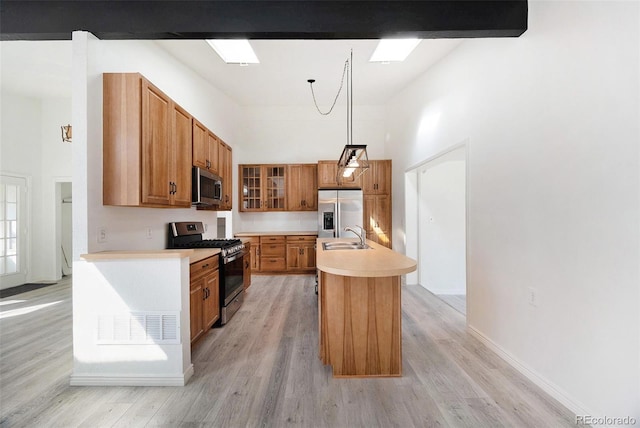 kitchen featuring pendant lighting, sink, appliances with stainless steel finishes, a kitchen island with sink, and a skylight