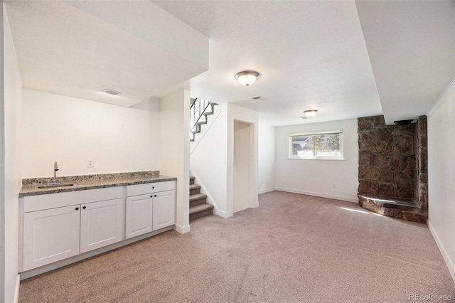 basement with sink, light colored carpet, and a textured ceiling