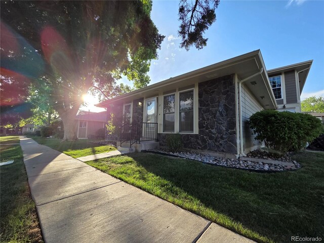 1250 S Monaco Pkwy Unit 17, Denver, CO 80224 - view of side of home featuring stone siding and a yard