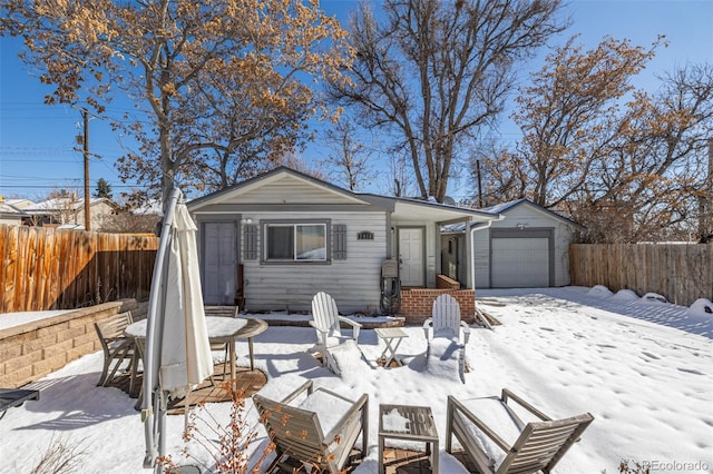 view of front of house featuring outdoor dining space, an attached garage, and fence