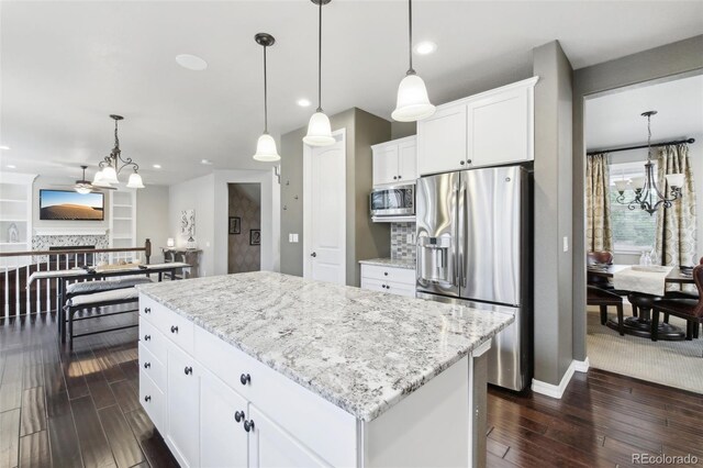 kitchen featuring pendant lighting, dark wood-type flooring, stainless steel appliances, and a center island