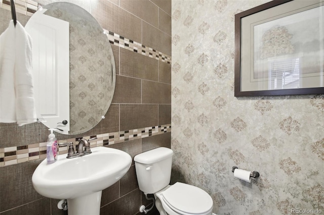 bathroom featuring tile walls, toilet, and sink