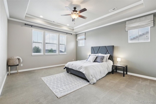 carpeted bedroom with a tray ceiling, ornamental molding, and ceiling fan