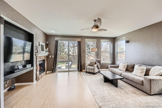 10774 Chadsworth Ln, Highlands Ranch, CO 80126 - living area with wood finished floors, healthy amount of natural light, ceiling fan, a stone fireplace, and a textured wall