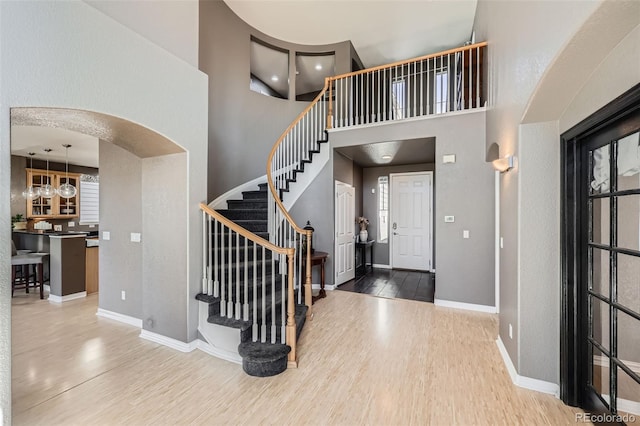 10774 Chadsworth Ln, Highlands Ranch, CO 80126 - entryway featuring wood finished floors, stairs, baseboards, a high ceiling, and arched walkways