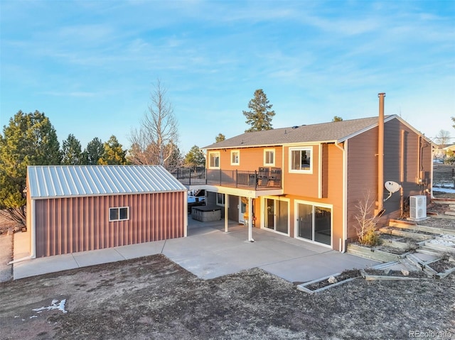 rear view of property with a balcony, an outdoor structure, and a patio