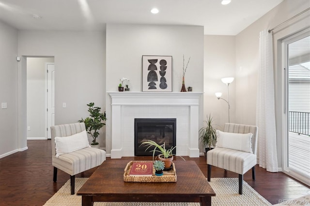 living room with recessed lighting, baseboards, a brick fireplace, and wood finished floors
