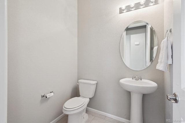bathroom with toilet, baseboards, and tile patterned flooring
