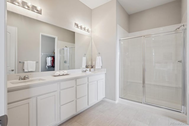 full bath featuring a sink, a stall shower, double vanity, and a spacious closet