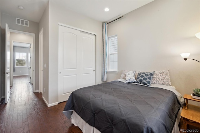 bedroom featuring baseboards, a closet, dark wood-style flooring, and visible vents