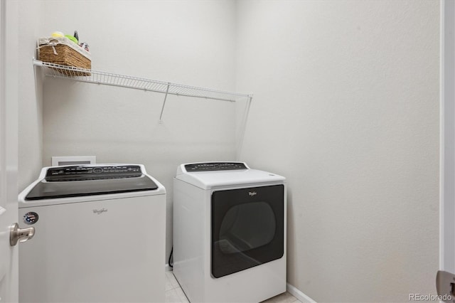 clothes washing area featuring laundry area, baseboards, light tile patterned floors, and washer and dryer