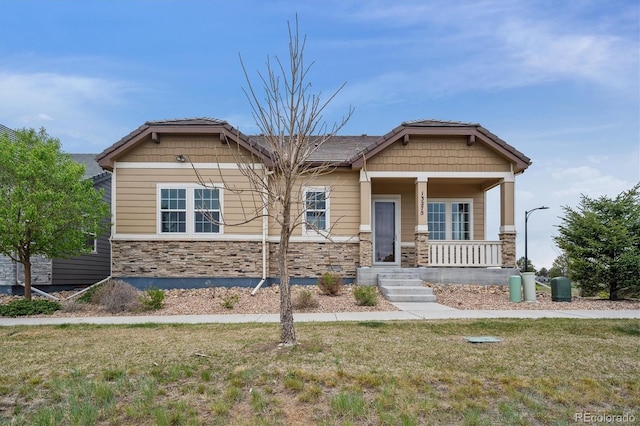 craftsman inspired home with a front yard, covered porch, and stone siding