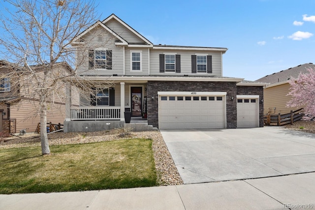 4830 S Versailles St, Aurora, CO 80015 - view of front of home with a porch, a front lawn, concrete driveway, a garage, and stone siding