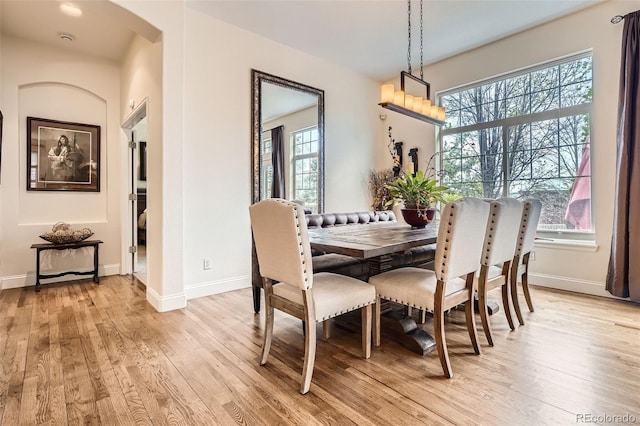 dining area with light wood-style flooring, plenty of natural light, and baseboards