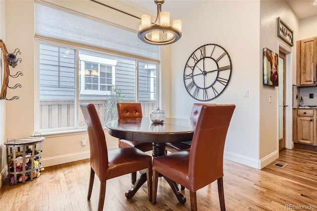dining area featuring light wood-style floors, a chandelier, and baseboards