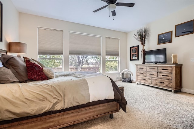 carpeted bedroom featuring multiple windows, a ceiling fan, and baseboards