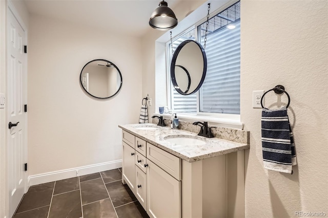 bathroom with double vanity, baseboards, and tile patterned flooring