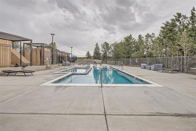 community pool with a patio and fence