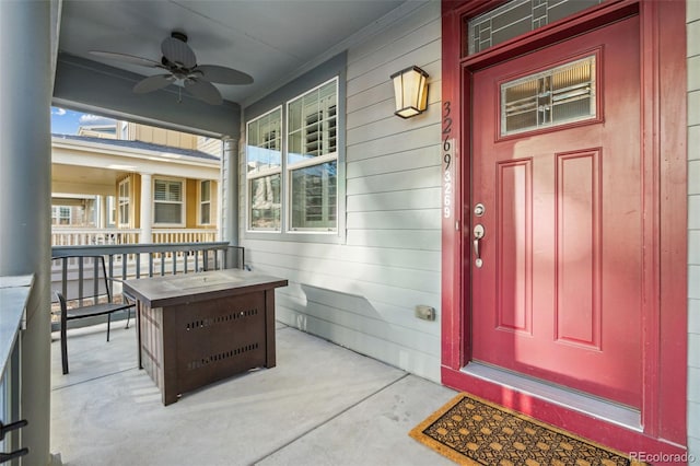 view of exterior entry featuring a porch and a ceiling fan