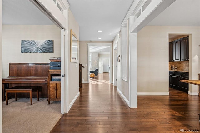 hall with dark wood-type flooring, recessed lighting, and baseboards