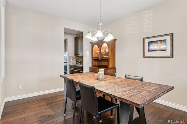 dining space featuring a chandelier, dark wood-style flooring, lofted ceiling, and baseboards