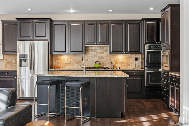 kitchen with double oven, dark wood-style flooring, stainless steel fridge, and light stone countertops