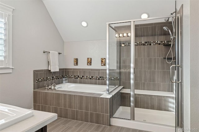 bathroom featuring a stall shower, vaulted ceiling, and a garden tub